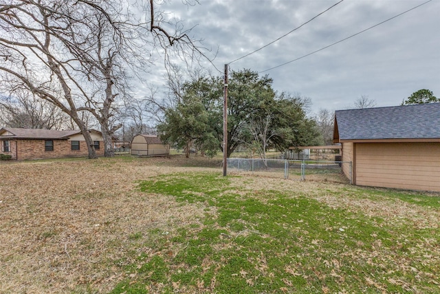 view of yard featuring a storage shed, fence, and an outbuilding