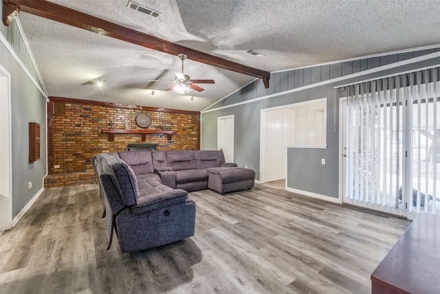 living area featuring vaulted ceiling with beams, a textured ceiling, wood finished floors, and visible vents