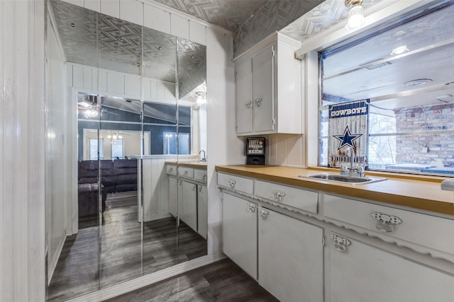 kitchen featuring dark wood finished floors, white cabinetry, light countertops, and a sink