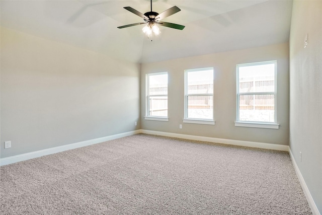 carpeted spare room with plenty of natural light, ceiling fan, and vaulted ceiling