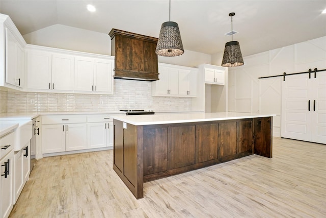 kitchen featuring white cabinetry, a barn door, a center island, and decorative light fixtures