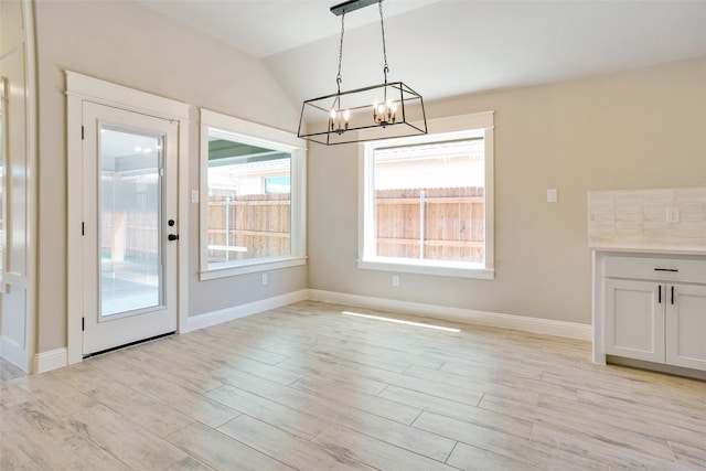 unfurnished dining area featuring vaulted ceiling and light hardwood / wood-style floors