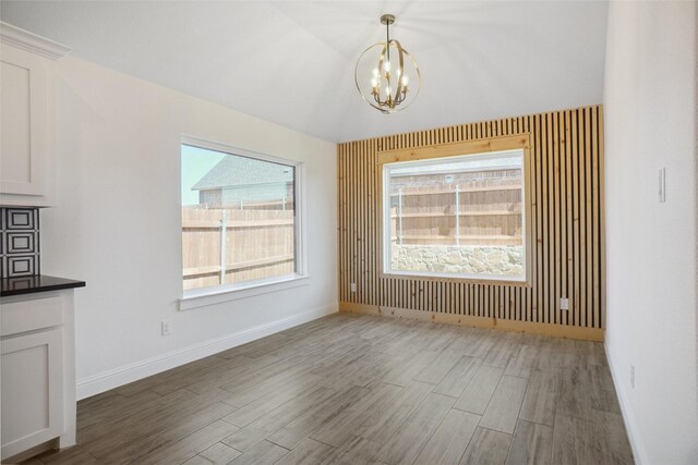 unfurnished dining area featuring dark hardwood / wood-style floors and a chandelier