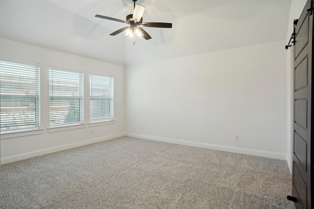 unfurnished bedroom featuring a barn door, carpet flooring, and ceiling fan