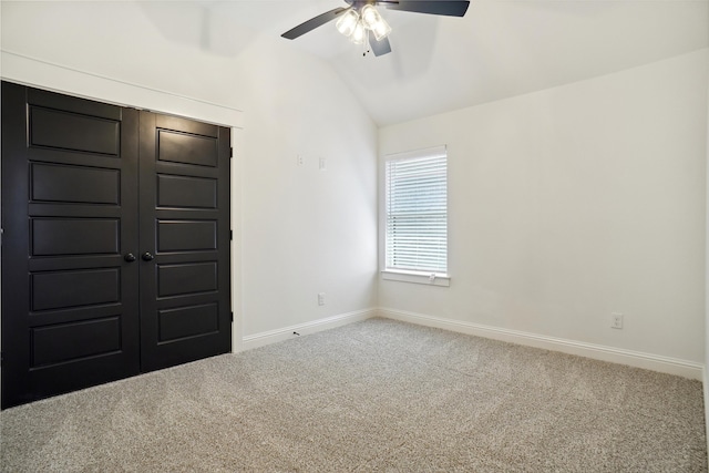 spare room with ceiling fan, lofted ceiling, and carpet flooring