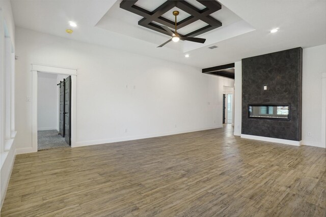 unfurnished living room with ceiling fan, hardwood / wood-style floors, beamed ceiling, coffered ceiling, and a high end fireplace