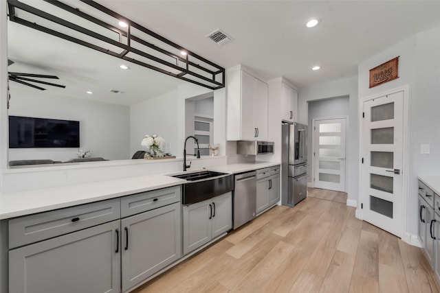 kitchen with stainless steel appliances, light hardwood / wood-style floors, sink, gray cabinets, and ceiling fan