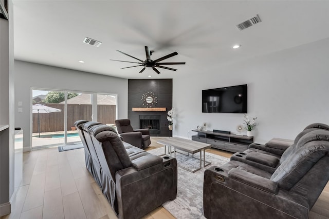 living room with ceiling fan and a large fireplace