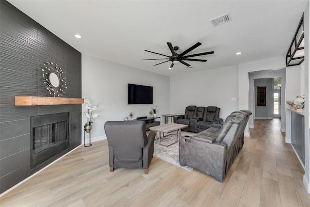 living room featuring ceiling fan, a fireplace, and light hardwood / wood-style flooring