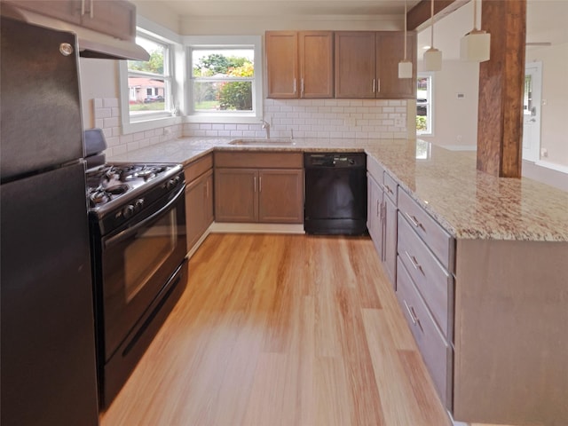 kitchen with kitchen peninsula, hanging light fixtures, sink, black appliances, and decorative backsplash