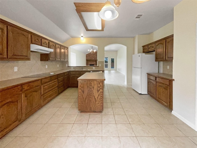 kitchen featuring lofted ceiling, backsplash, a kitchen island, black electric stovetop, and a chandelier