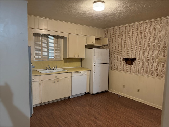 kitchen with dark hardwood / wood-style flooring, white appliances, sink, and a textured ceiling