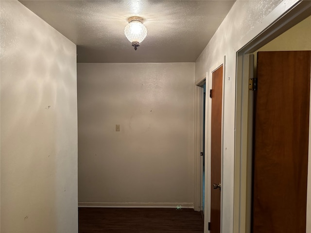 corridor with a textured ceiling and dark hardwood / wood-style flooring