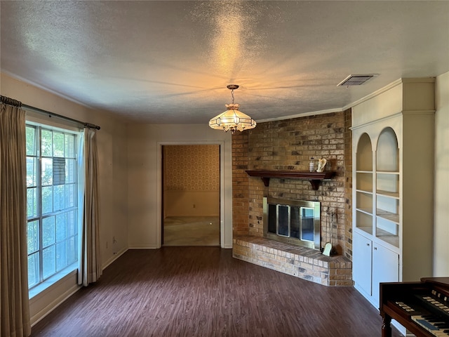 unfurnished living room with a textured ceiling, dark hardwood / wood-style flooring, a brick fireplace, and built in features