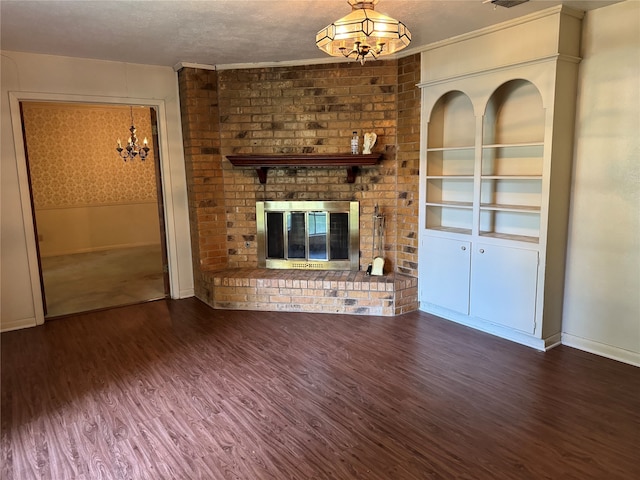 unfurnished living room featuring dark hardwood / wood-style floors, a fireplace, an inviting chandelier, and a textured ceiling