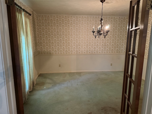 spare room featuring carpet flooring and an inviting chandelier