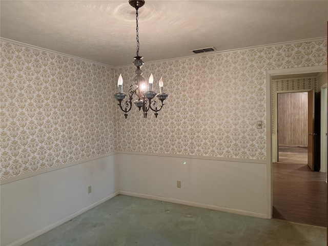 carpeted spare room featuring a chandelier and crown molding