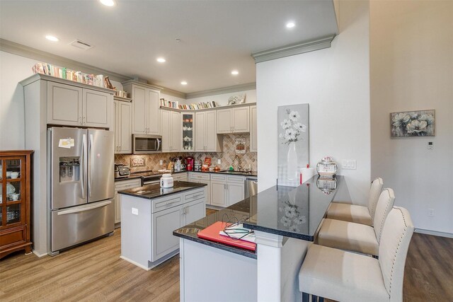 kitchen featuring sink, backsplash, kitchen peninsula, a kitchen bar, and appliances with stainless steel finishes