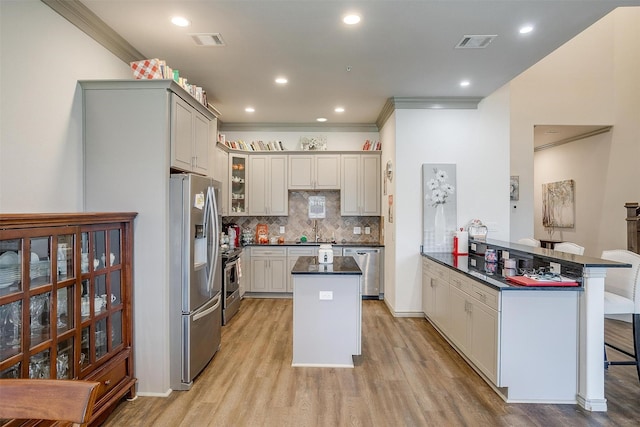 kitchen featuring sink, kitchen peninsula, light hardwood / wood-style floors, a breakfast bar, and appliances with stainless steel finishes