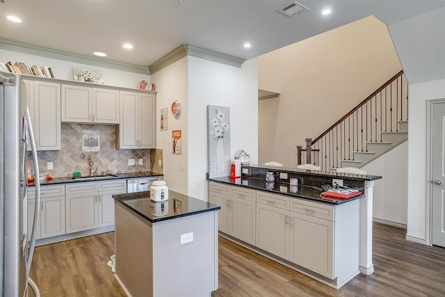 kitchen featuring kitchen peninsula, light wood-type flooring, stainless steel appliances, and ornamental molding