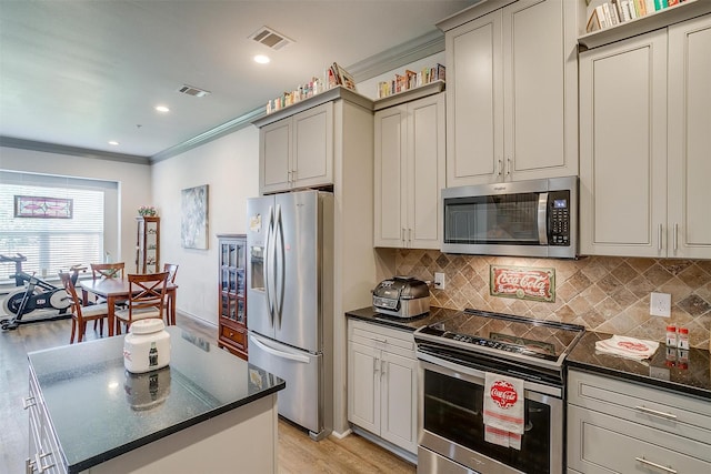 kitchen with decorative backsplash, gray cabinets, light wood-type flooring, ornamental molding, and appliances with stainless steel finishes