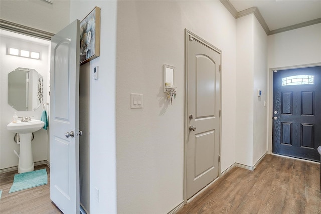 foyer entrance with hardwood / wood-style floors, ornamental molding, and sink