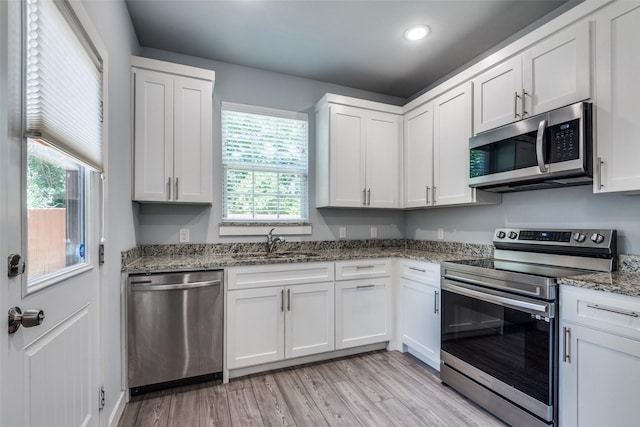 kitchen featuring white cabinets, appliances with stainless steel finishes, light wood-type flooring, and sink