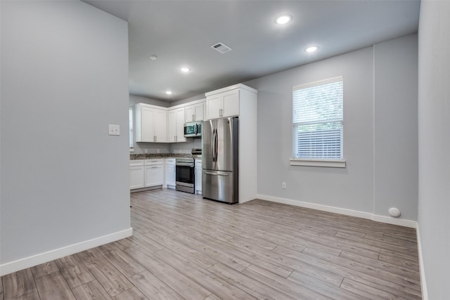 kitchen with stainless steel appliances, white cabinetry, and light wood-type flooring