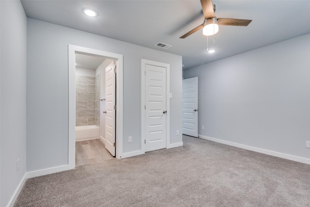 unfurnished bedroom featuring ensuite bath, light colored carpet, a closet, and ceiling fan