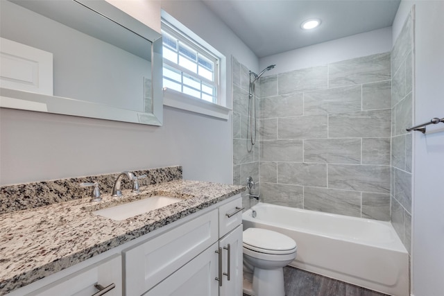 full bathroom with tiled shower / bath, wood-type flooring, vanity, and toilet