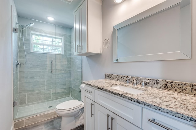 bathroom featuring vanity, wood-type flooring, toilet, and a shower with shower door