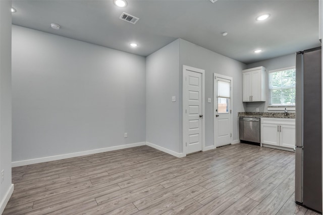 kitchen featuring appliances with stainless steel finishes, light stone counters, white cabinets, and light hardwood / wood-style floors