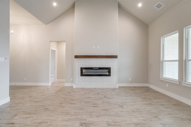 unfurnished living room featuring a fireplace, high vaulted ceiling, and plenty of natural light