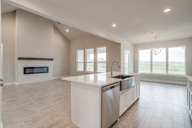 kitchen featuring a center island with sink, dishwasher, a wealth of natural light, and a tile fireplace