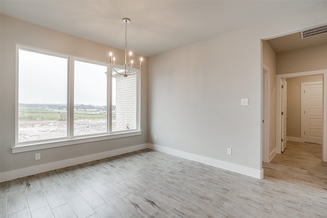 spare room featuring light hardwood / wood-style flooring and an inviting chandelier