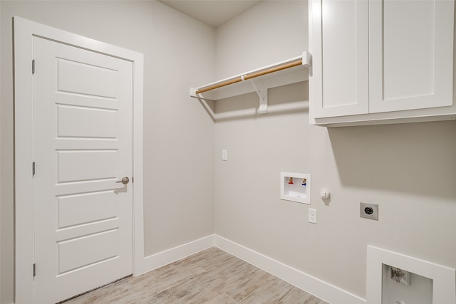 clothes washing area featuring gas dryer hookup, light wood-type flooring, hookup for an electric dryer, washer hookup, and cabinets