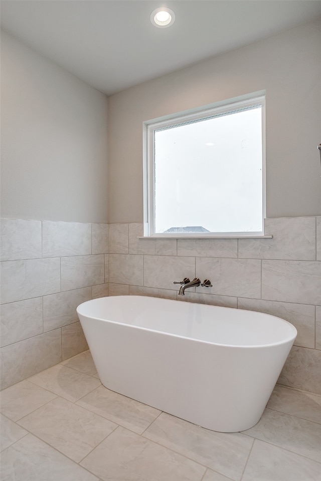 bathroom with a bath, tile walls, and tile patterned flooring