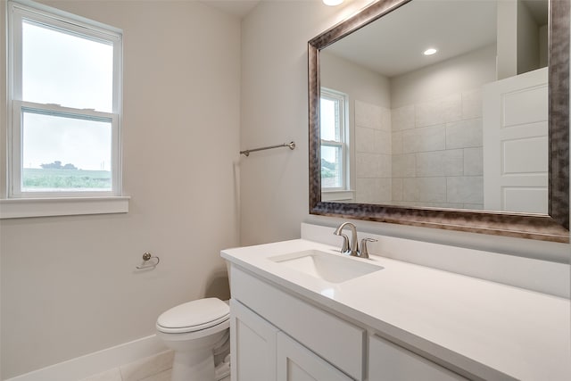 bathroom with vanity, toilet, a healthy amount of sunlight, and tile patterned flooring