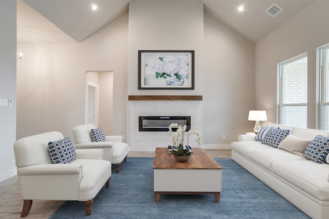 living room with vaulted ceiling, hardwood / wood-style floors, and a tile fireplace