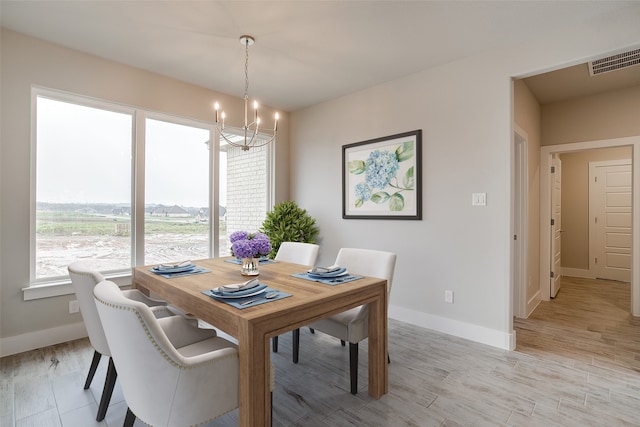 dining area with light wood-type flooring and an inviting chandelier