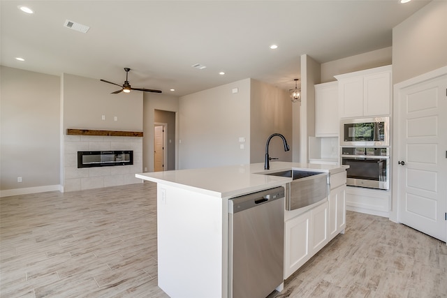 kitchen with appliances with stainless steel finishes, sink, a center island with sink, and white cabinets