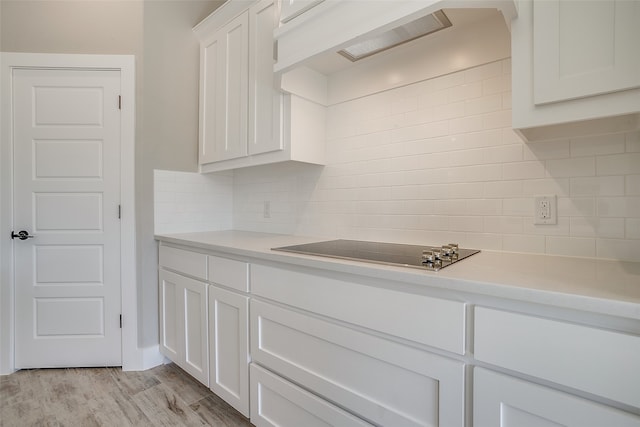 kitchen with tasteful backsplash, white cabinetry, light hardwood / wood-style floors, and black electric stovetop