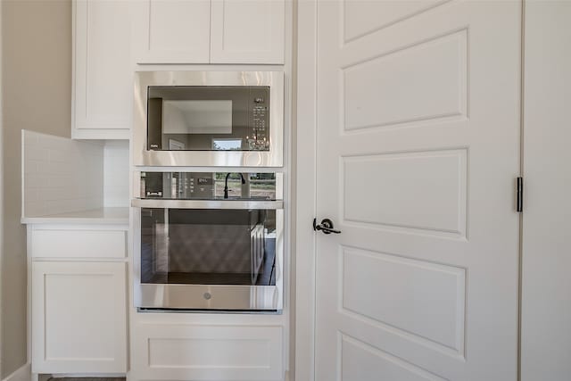 kitchen featuring appliances with stainless steel finishes, decorative backsplash, and white cabinets