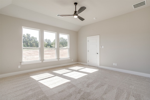 empty room with ceiling fan, vaulted ceiling, and light colored carpet