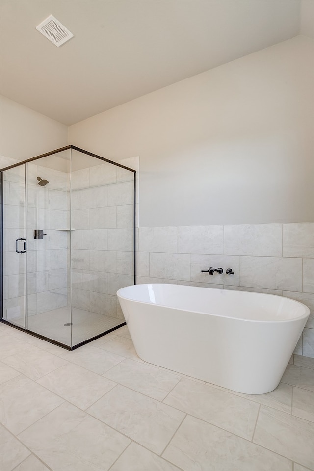 bathroom with tile walls, tile patterned floors, and separate shower and tub