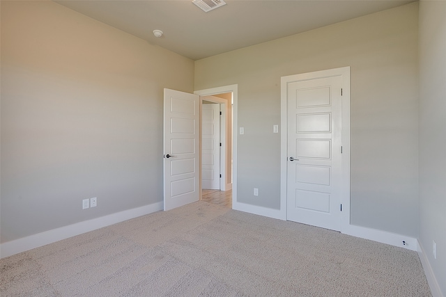 unfurnished bedroom with a closet and light carpet