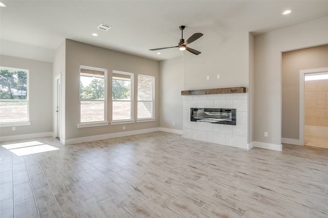 unfurnished living room with light wood-type flooring, a tiled fireplace, and ceiling fan