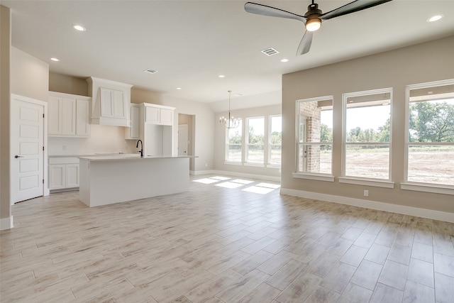 kitchen featuring white cabinetry, light hardwood / wood-style floors, a healthy amount of sunlight, and an island with sink