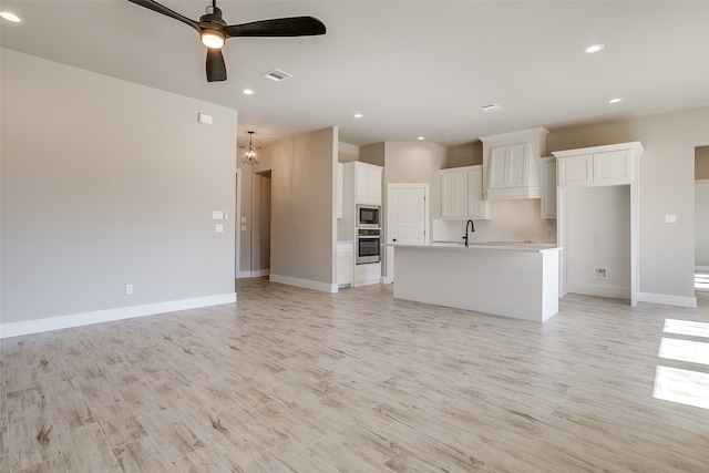 unfurnished living room with sink, light hardwood / wood-style floors, and ceiling fan with notable chandelier