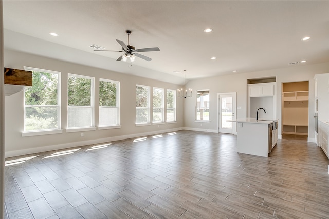 unfurnished living room featuring ceiling fan with notable chandelier, light hardwood / wood-style floors, and sink